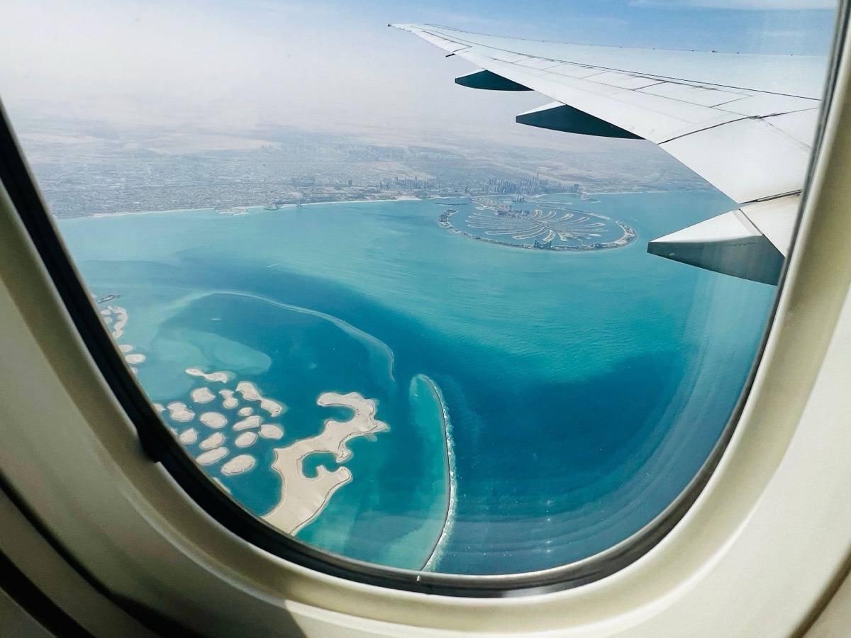 View through an aircraft window of the wing over the Dubai coast, with Palm Jumeirah and The World islands in the sea below, the trip a founder makes for the UAE steps