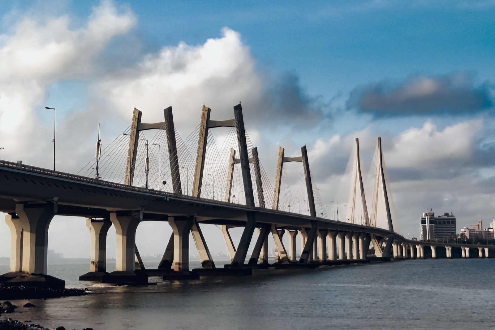 The Bandra Worli Sea Link crossing the water in Mumbai under a cloudy blue sky, for a guide to setting up a Dubai company from India