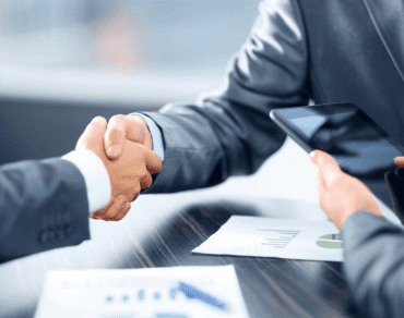 Two people shaking hands across a desk at the end of a bank meeting